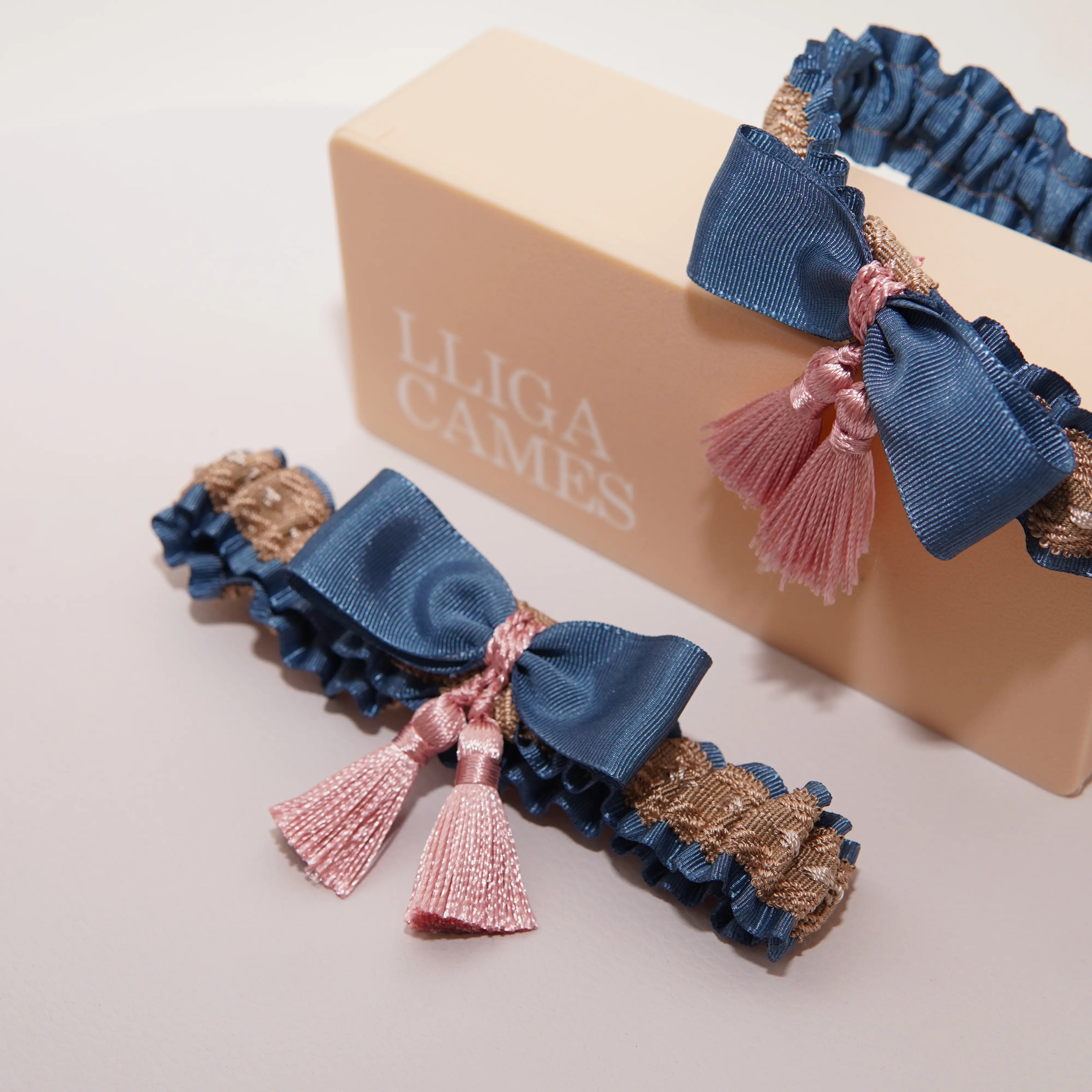 Lligacames Borles azul y marrón con borlas rosa